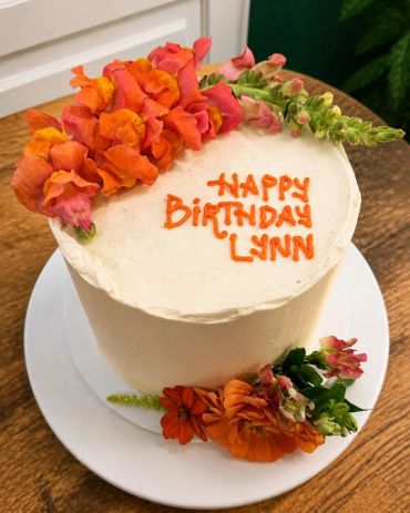 Birthday cake with orange flowers and message.