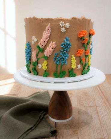 Floral decorated cake with colorful flowers on a pedestal.