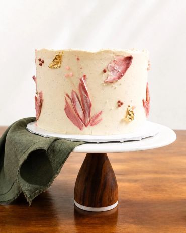 Elegant cake with floral decorations on a wooden stand.