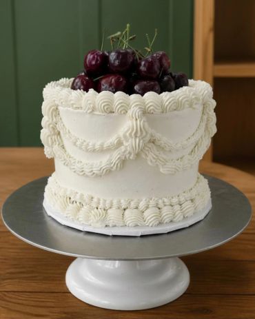 White frosted cake with cherries on top.