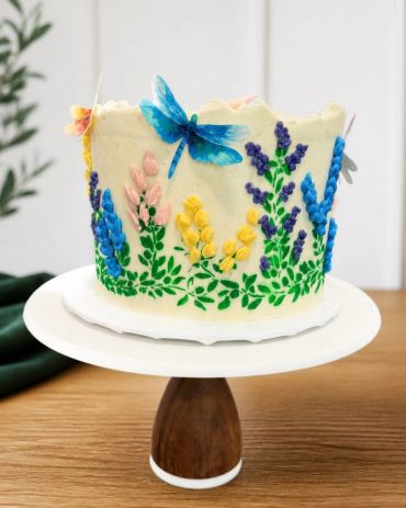 Elegant floral cake with a blue butterfly decoration.