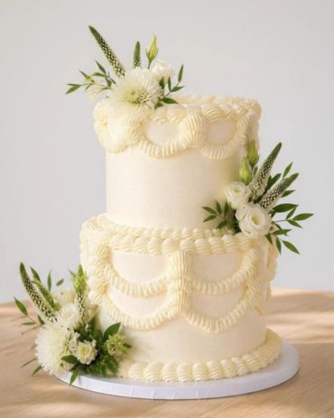 Elegant two-tier white cake with floral decorations.