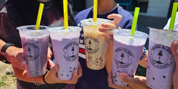Group holding boba tea drinks with colorful straws.