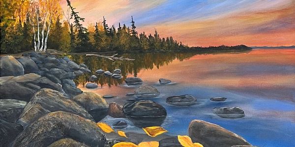 Serene lakeside at sunset with autumn leaves on rocks and golden trees.