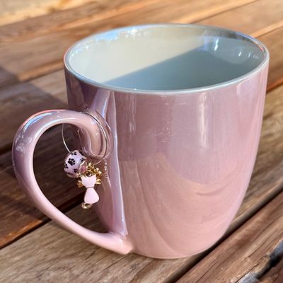 Iridescent pink coffee mug with wine charm hanging from the handle with bead, kitty cat, and letter