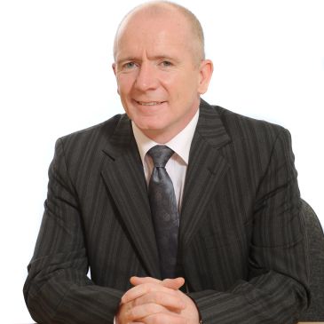 Middle-aged man in a pinstripe suit smiling at the camera.