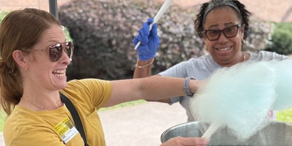 Two women making cotton candy outdoors.
