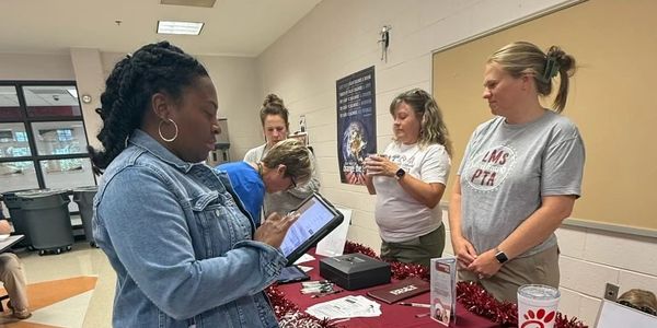 People gathered around a table with informational materials indoors.