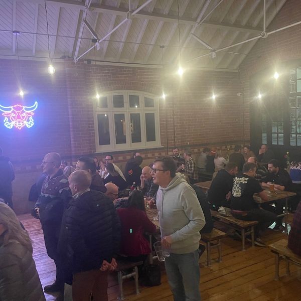 People socializing in a cozy bar with neon bull sign and wooden interiors.