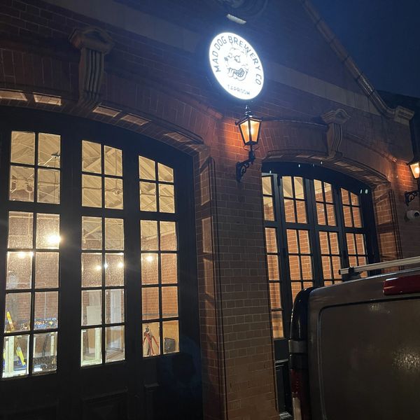Night view of Mad Dog Brewery Co. taproom with illuminated sign and vintage lamps.