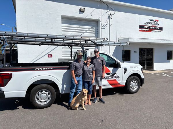 The James family, standing next to one of their business trucks, parked in front of their business.