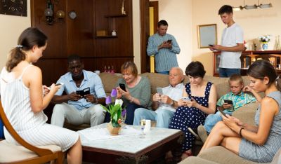 Family members sitting together, each focused on their smartphones.