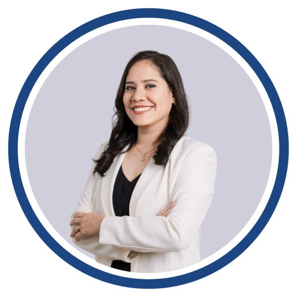 Confident woman in white blazer smiling with arms crossed.