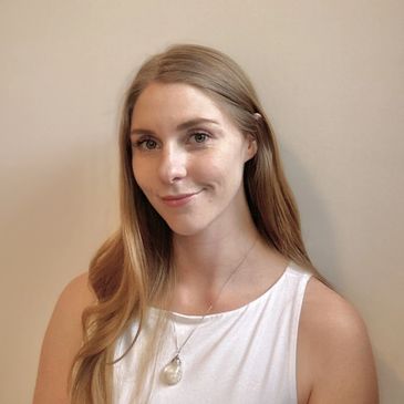 Young smiling woman with long blonde hair wearing a white top and necklace.