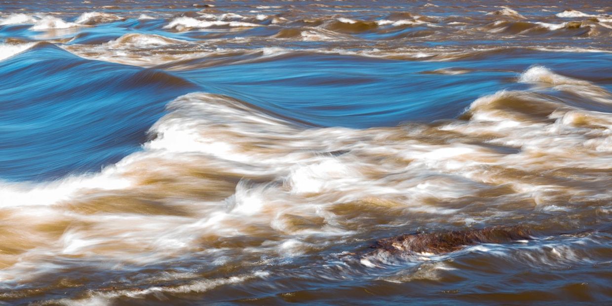 A panoramic close up of blue Susquehanna River currents and white caps using slow shutter technique.