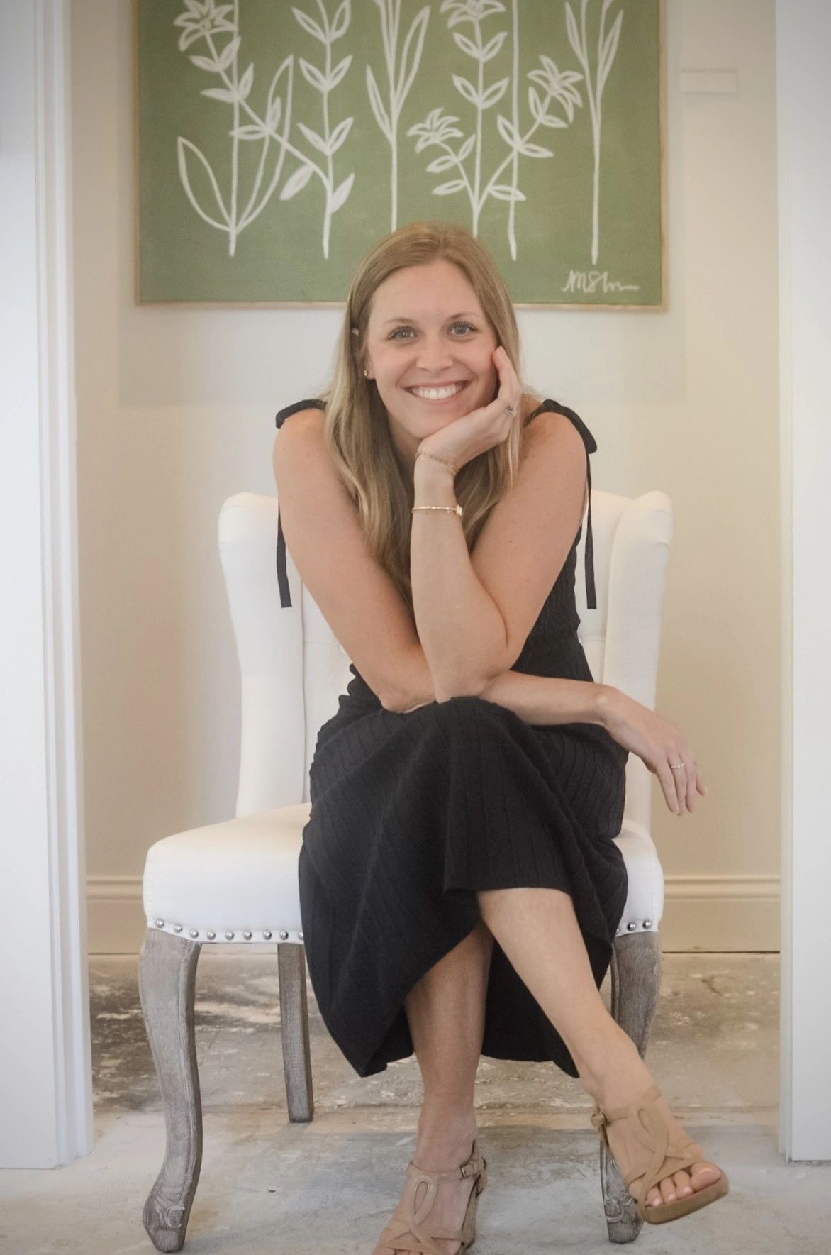 Woman in black dress smiling while seated.