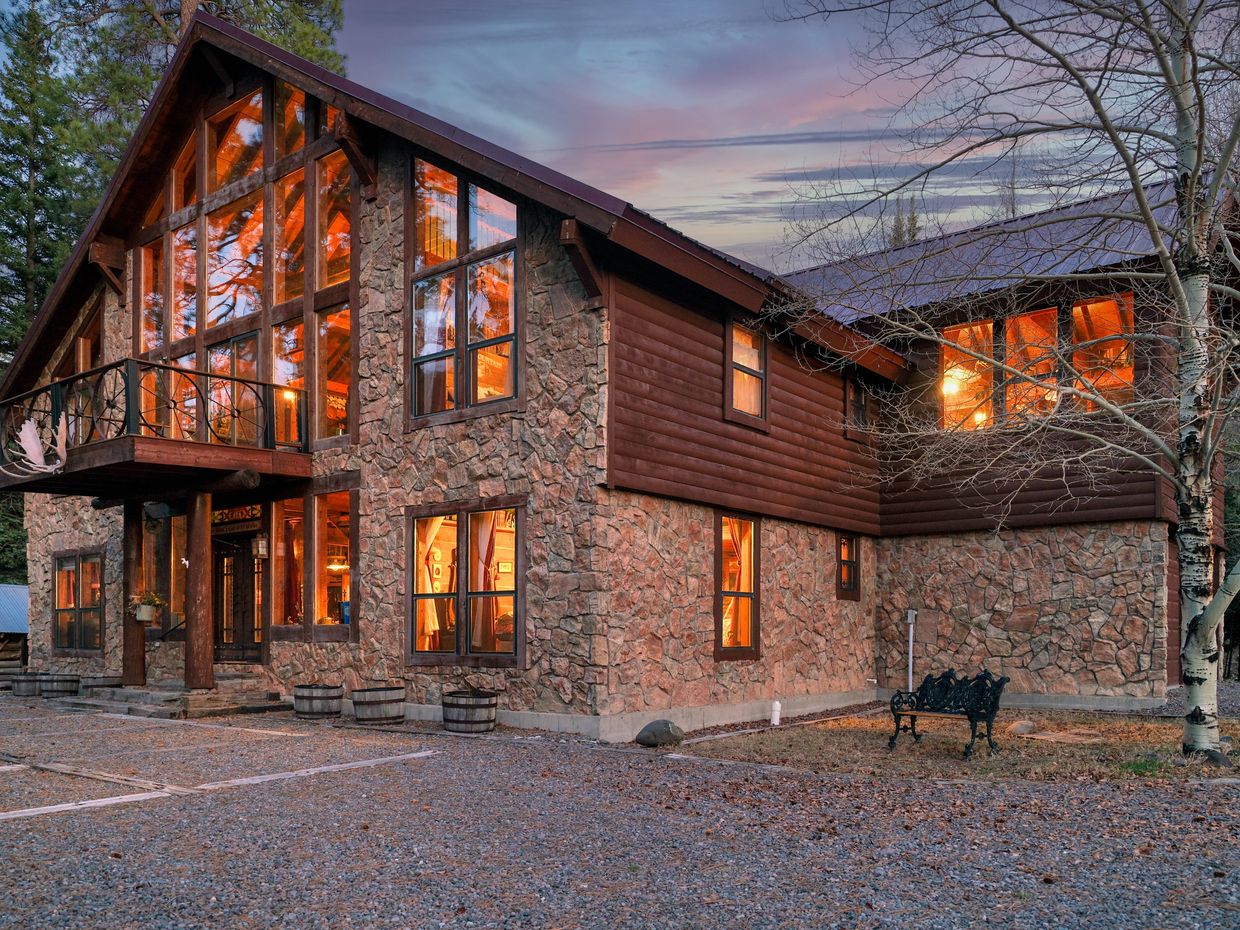 Rustic stone and wood cabin glowing warmly at dusk.