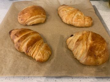 Four freshly baked croissants on parchment paper.