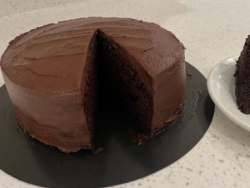 A chocolate cake with a slice missing on a black plate.