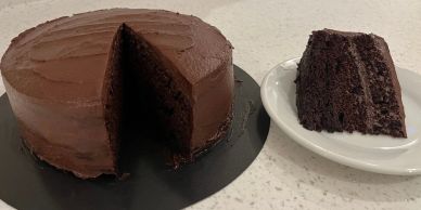 A chocolate cake with a slice missing on a black plate.