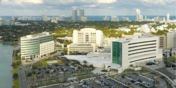 Aerial view of a modern hospital complex with multiple buildings and parking lots.