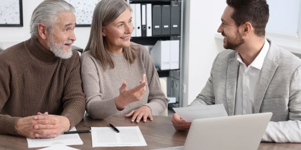 Elderly couple discussing documents with a professional man in an office.
