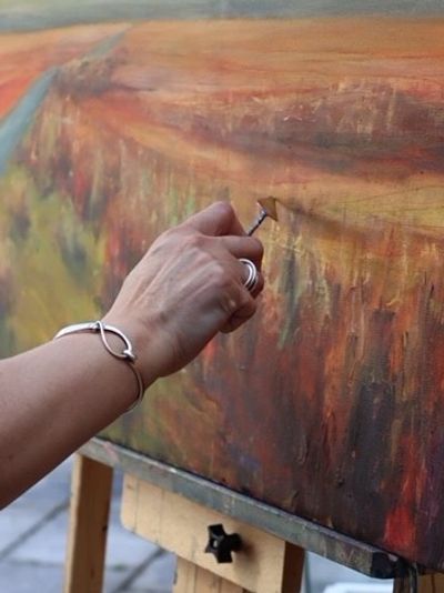 image of Judy's hand applying paint to a canvas using a pallet knife