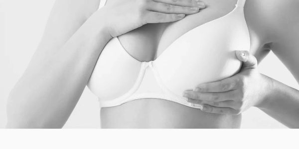 Woman in white bra performing a breast self-exam.