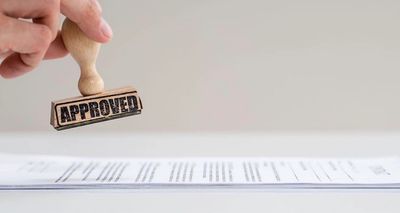 Hand stamping a document with an "APPROVED" stamp.