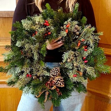 a person showing their handmade wreath, made during a wreath making workshop with lemonade events