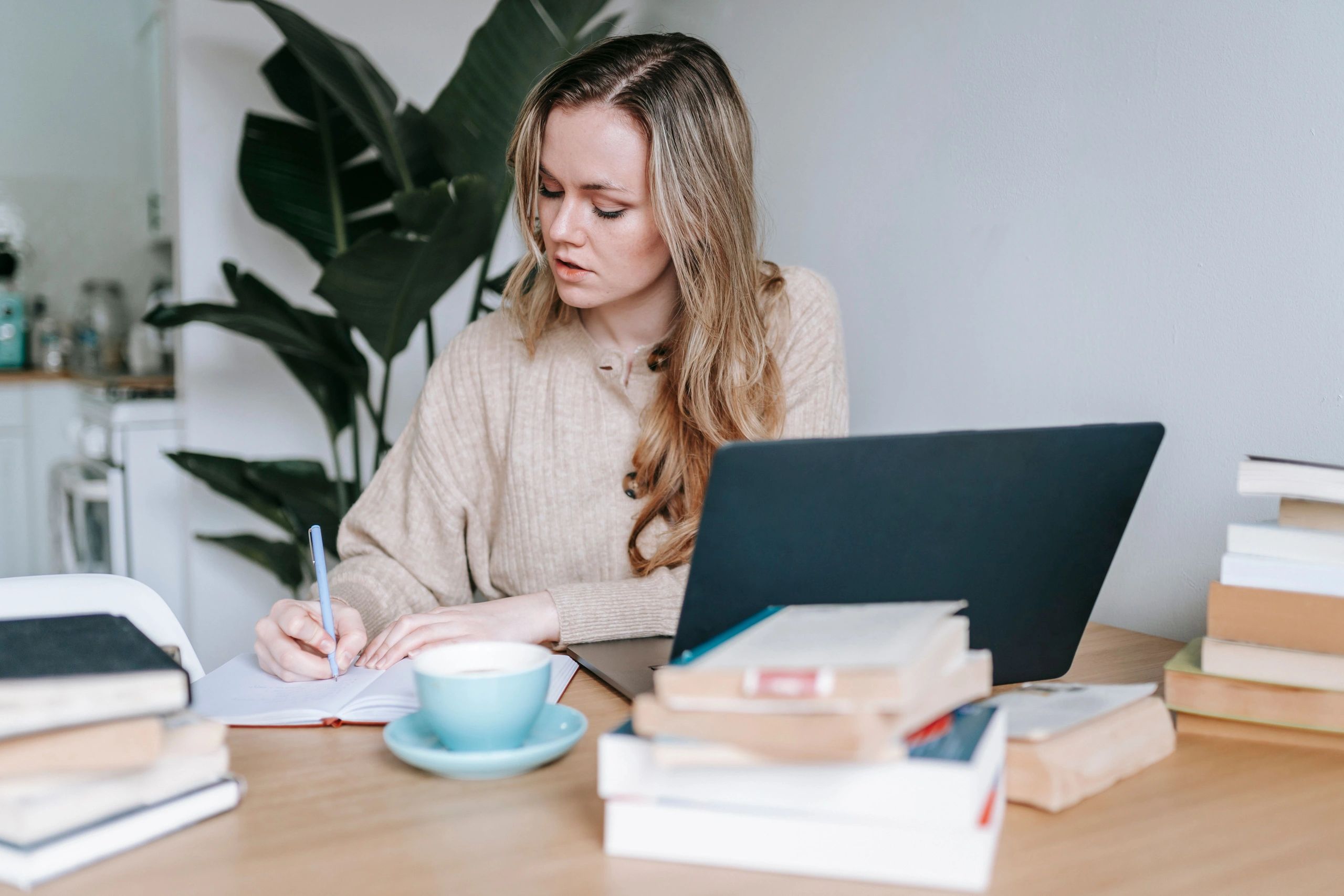 Young woman studying with books and laptop.