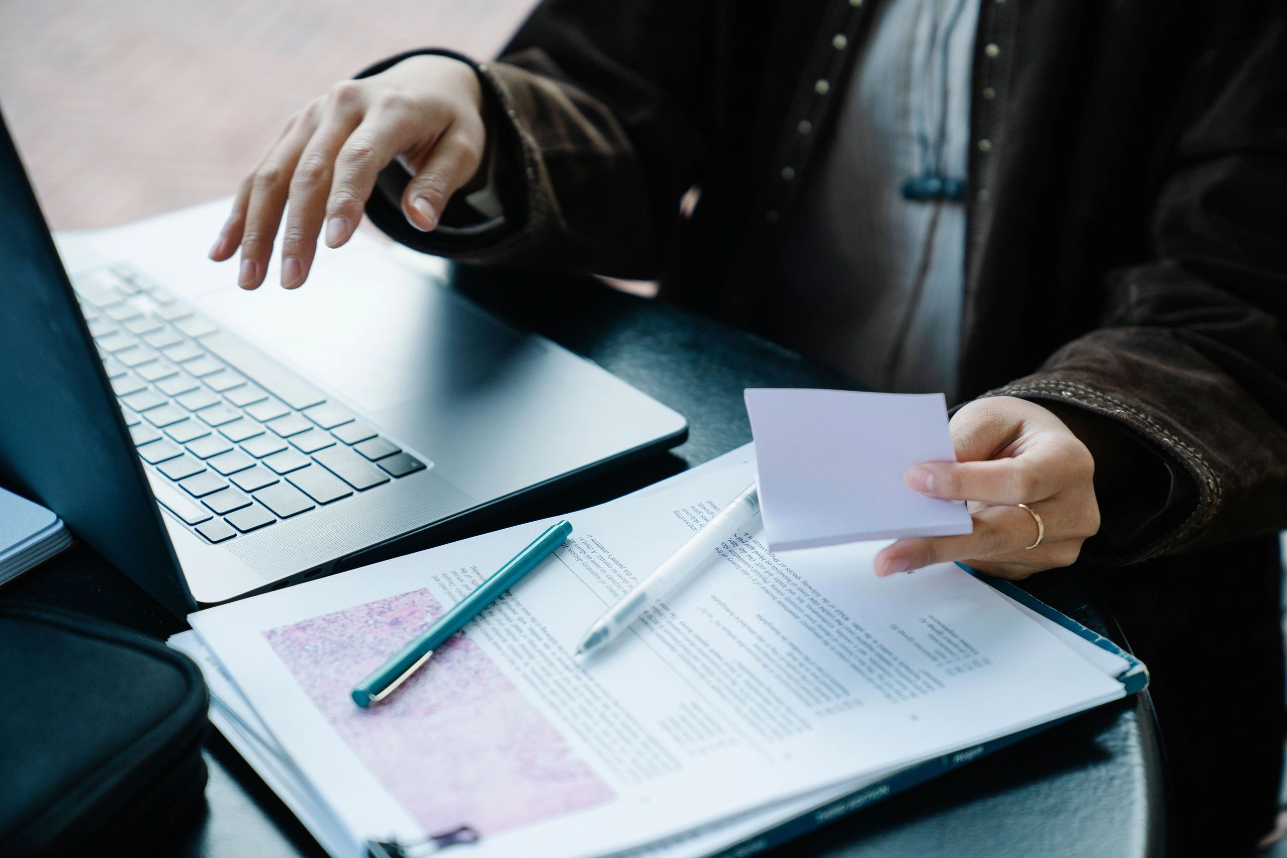 Person working with documents and laptop.