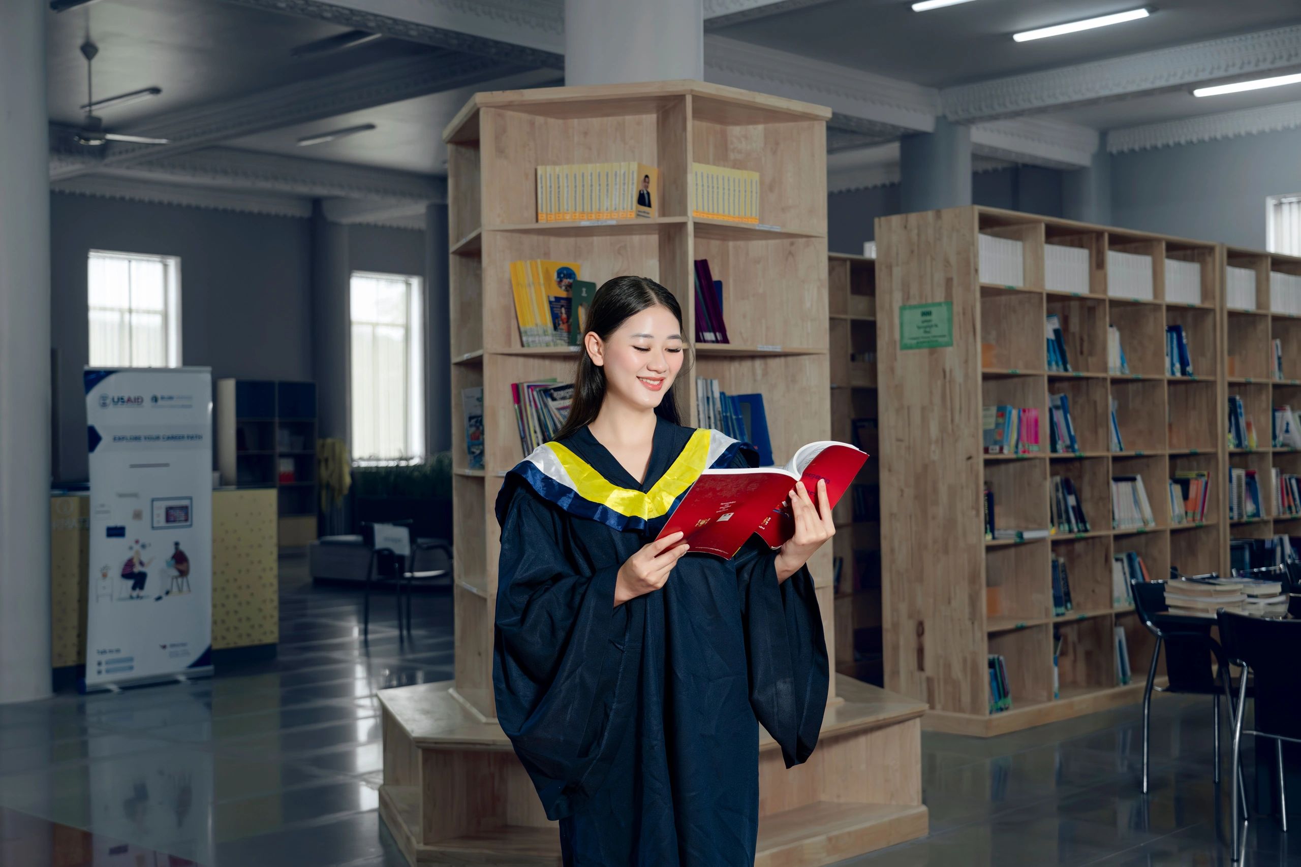 Graduation student reading a book in a library.
