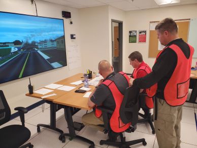 Three men in red vests participating in a simulation training.