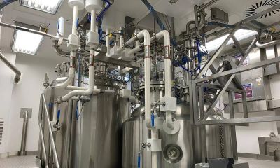 Industrial stainless steel tanks with connected pipes and valves in a factory setting.