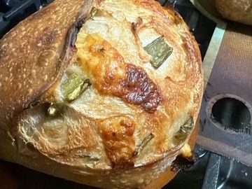 Freshly baked artisan bread with a golden crust and herbs on top.