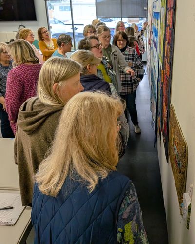 Group of people observing artwork on a wall.