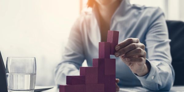 Smiling businesswoman building a successful financial chart using wooden pieces