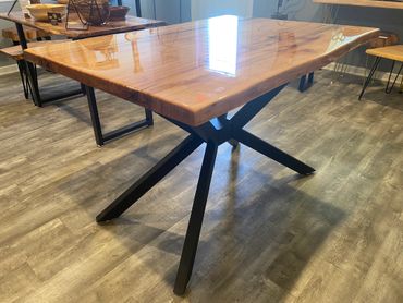 Polished wooden table with black metal legs on a wood floor.