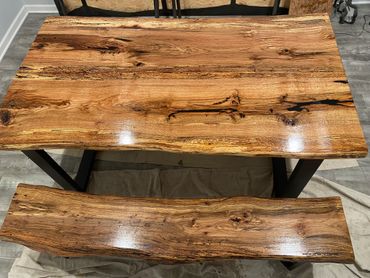 Polished wooden table and bench with natural grain and live edges.