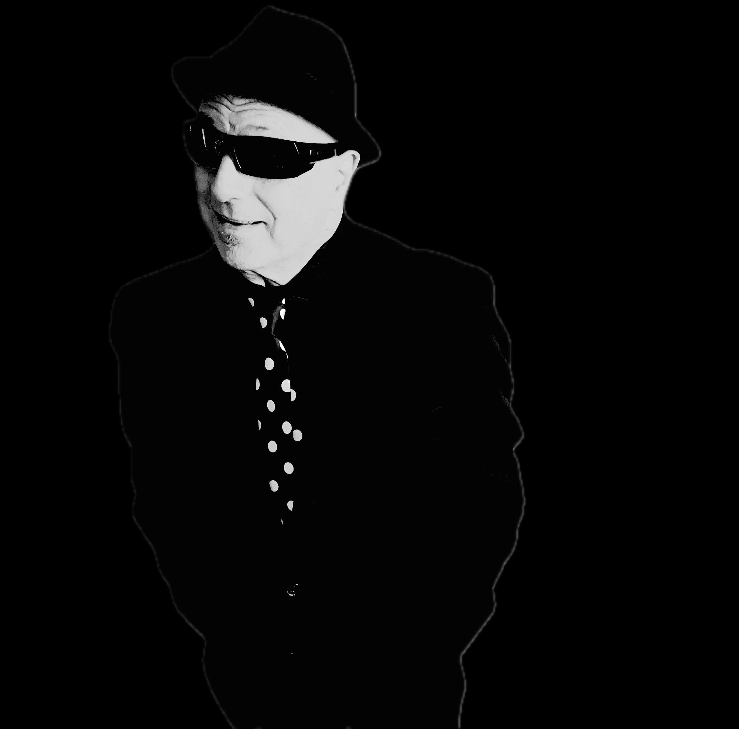 Man in sunglasses and hat with polka dot tie.