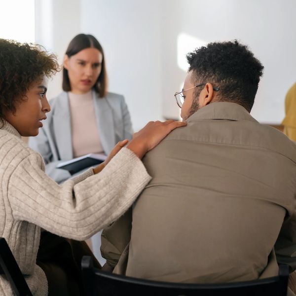 A woman comforting a man during a counseling session with a therapist.