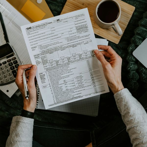 Person holding a U.S. tax form with a pen and coffee nearby.