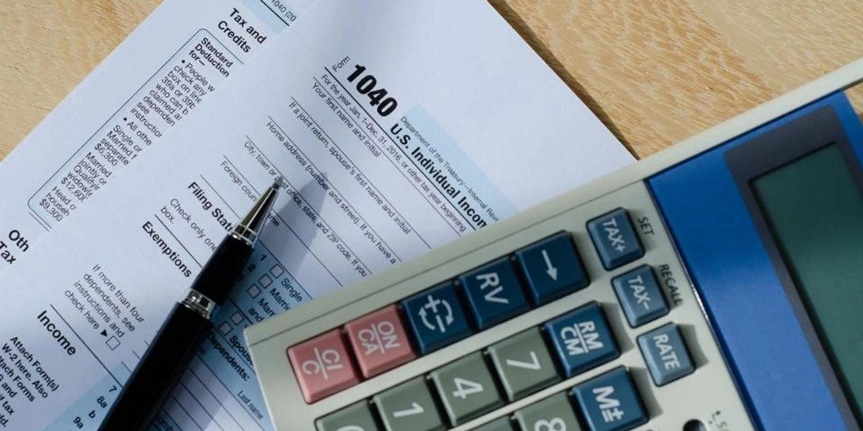 A 1040 U.S. Individual Income Tax form with a pen and calculator.