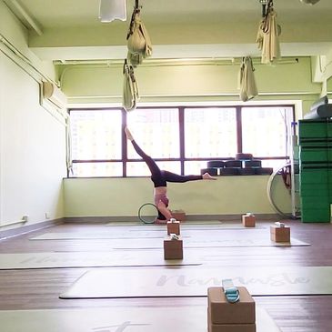 Person performing a headstand in a yoga studio with blocks and straps.
