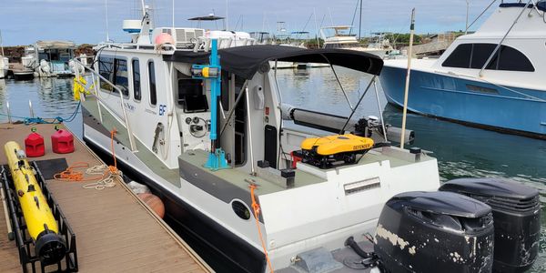 A white research boat docked at a marina with equipment on board.