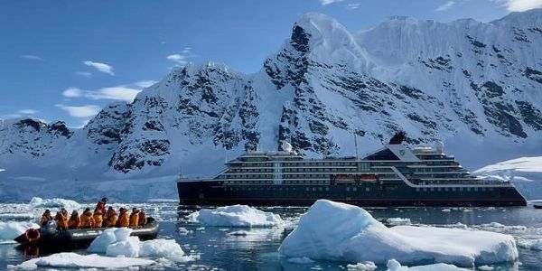 Tourists on a boat near an icy mountain cruise ship.
