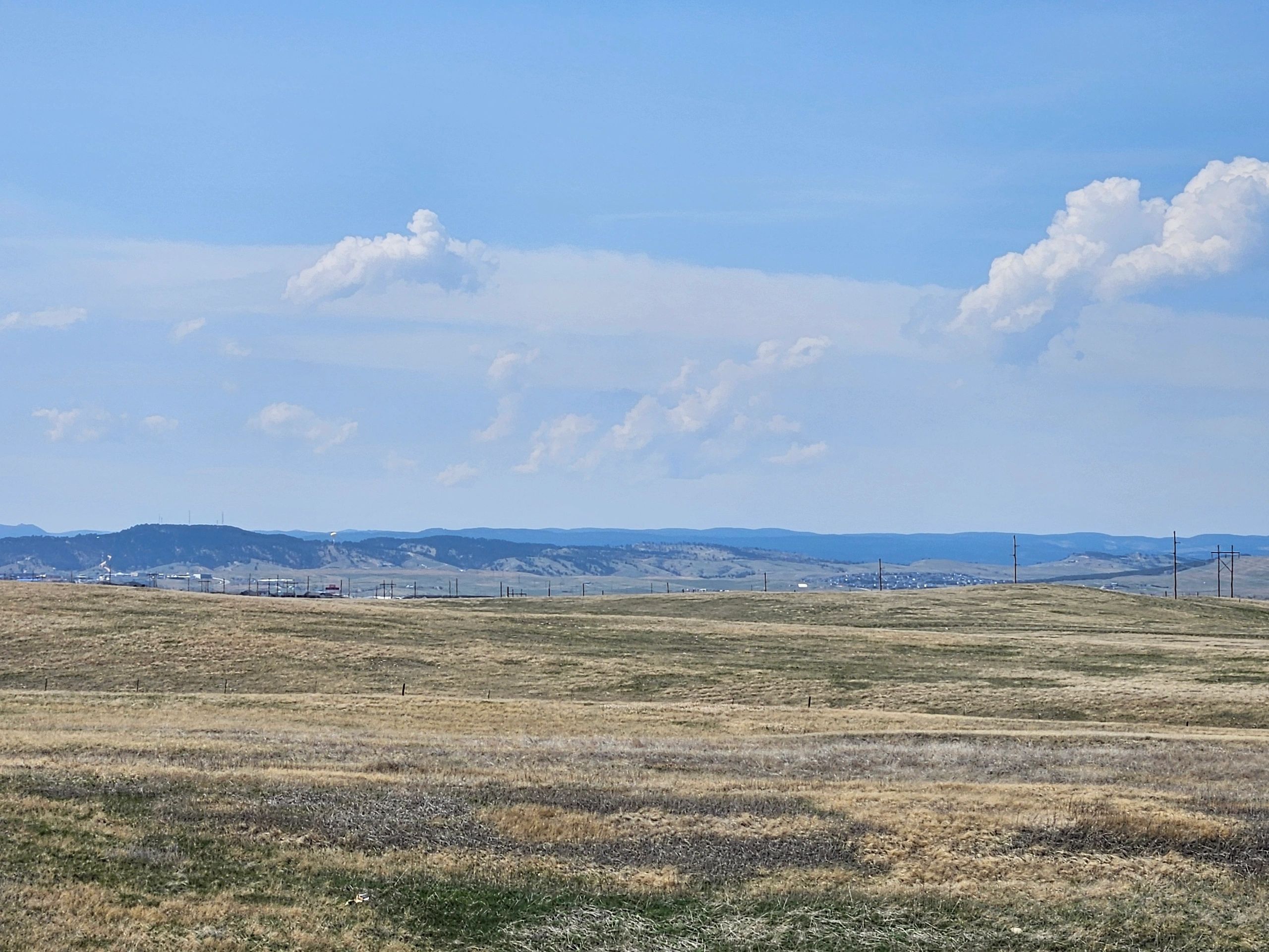 Wide open field and distant mountains under blue sky.