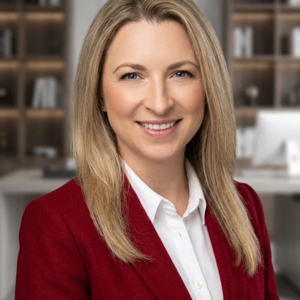 Professional woman in red blazer smiling.