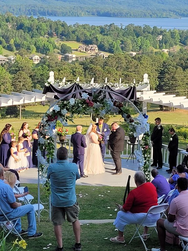 Outdoor wedding ceremony with scenic lake and forest backdrop.